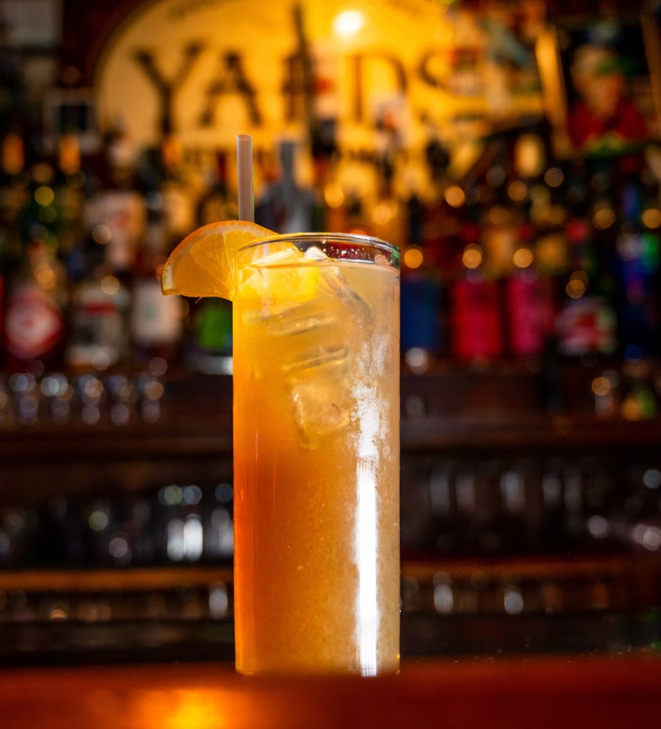 A Long Island Iced Tea with an orange slice at the bar