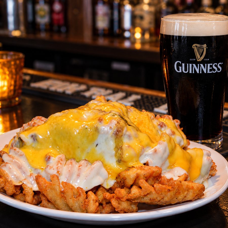 A plate of Spanish fries loaded with melted cheese, and a Guinness