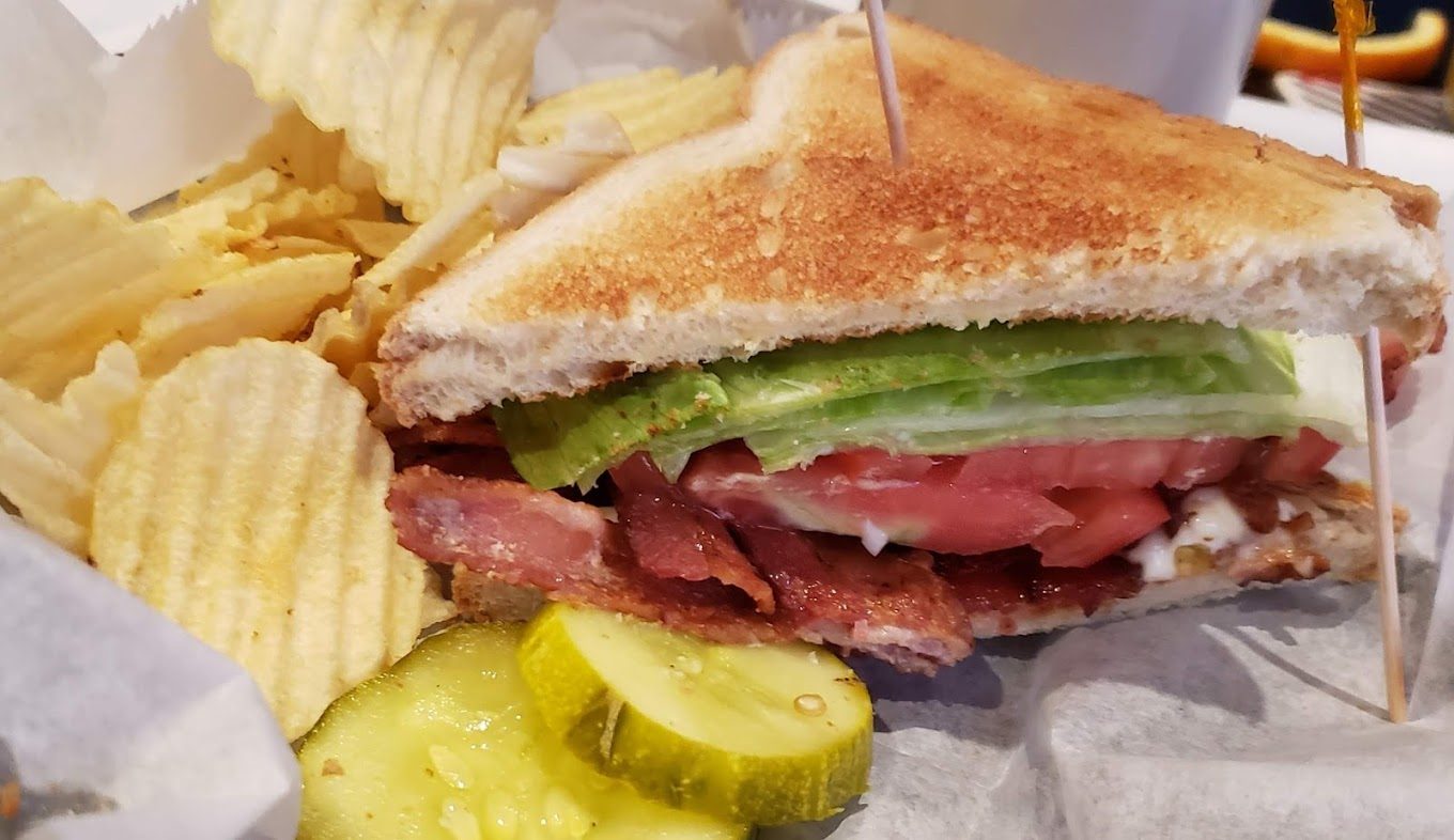 A BLT on toast with chips and a pickle