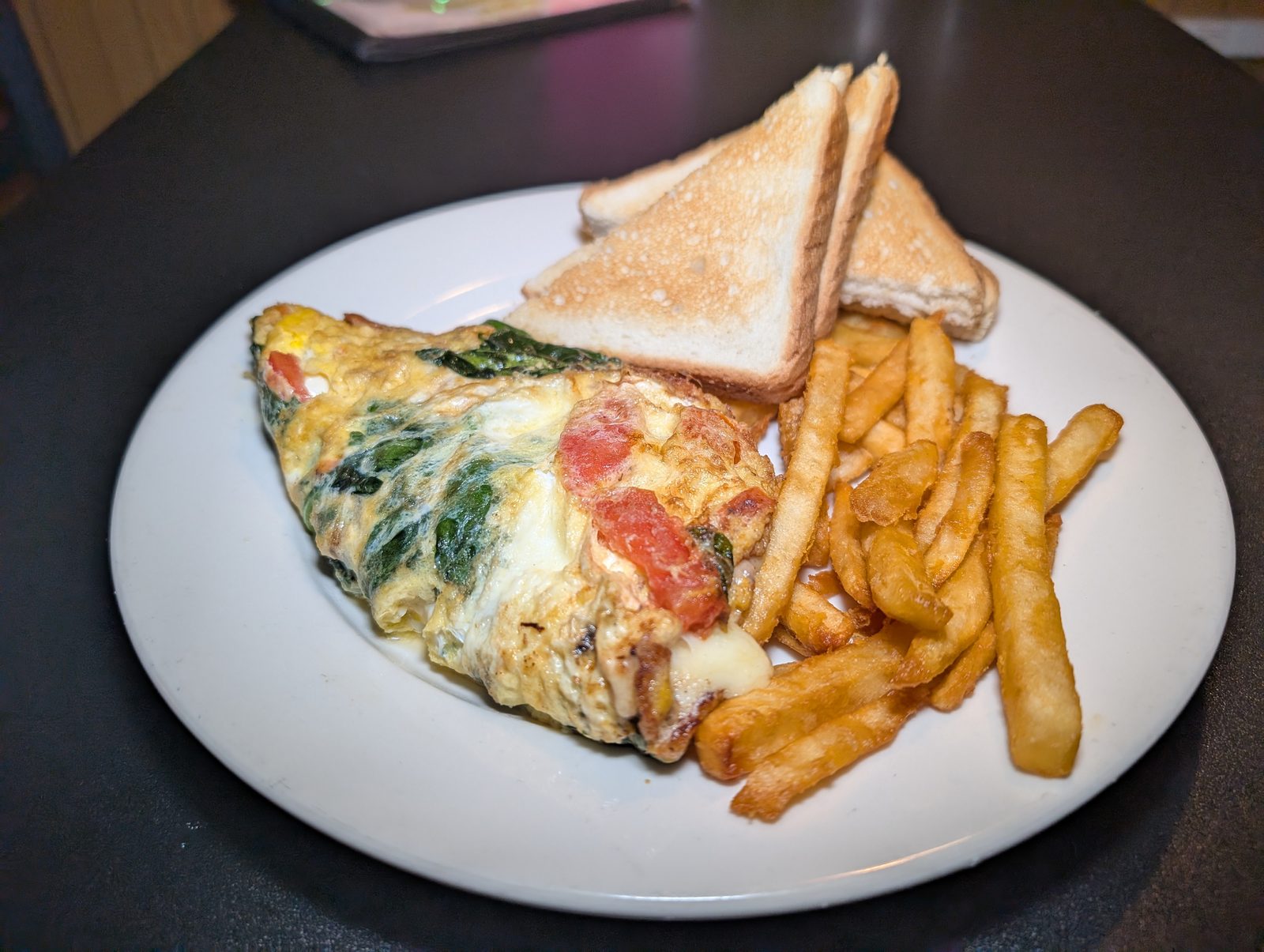 A breakfast plate with an omelet, toast and fries