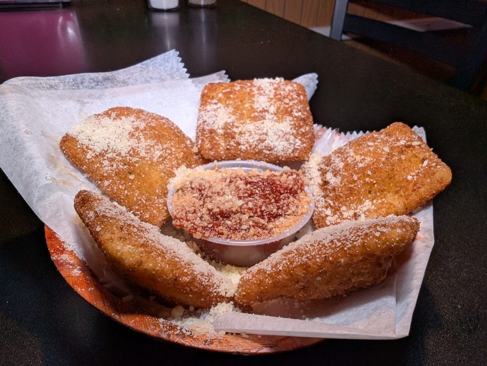 A basket of fried ravioli dusted with parmesan